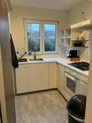 a kitchen with white cabinets and a sink and a window at Appartement confortable avec garage premier étage sans terrasse in Brussels