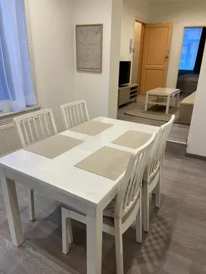 a white table and chairs with a white table and a room at Appartement confortable avec garage premier étage sans terrasse in Brussels