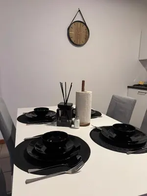 a table with black plates and a clock on the wall at Appartement de Luxe Entièrement Rénové - Proche Aéroport de Bruxelles, Quartier Chic in Brussels