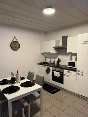 a kitchen with white cabinets and a table with chairs at Appartement de Luxe Entièrement Rénové - Proche Aéroport de Bruxelles, Quartier Chic in Brussels
