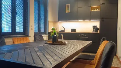 a dining room table with chairs and a kitchen at Royal South II - Stylish apartment in Antwerp Zuid in Antwerp
