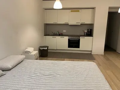 a bedroom with a bed and a kitchen with white cabinets at Brussels studio in Brussels
