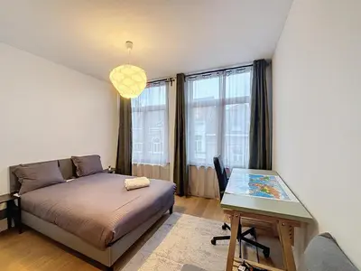 a bedroom with a bed and a desk with a table at Penthouse Cinquantenaire in Brussels