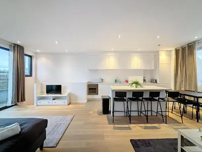 a kitchen and living room with white cabinets and a table at Penthouse Cinquantenaire in Brussels