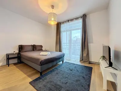 a bedroom with a bed and a large window at Penthouse Cinquantenaire in Brussels