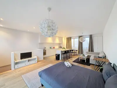 a large living room with a blue bed and a kitchen at Penthouse Cinquantenaire in Brussels