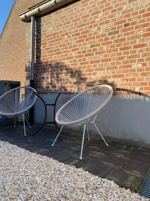 two metal benches sitting next to a brick wall at The Conservatory, a cosy private attic located central between Ghent Antwerp Brussels in Lokeren