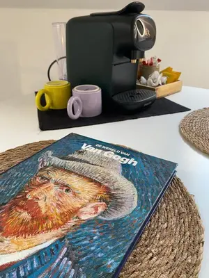 a book sitting on a table next to a coffee maker at The Conservatory, a cosy private attic located central between Ghent Antwerp Brussels in Lokeren