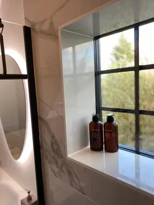 two bottles of soap sitting on a shelf next to a mirror at The Conservatory, a cosy private attic located central between Ghent Antwerp Brussels in Lokeren