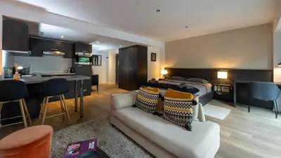 a hotel room with a bed and a couch and a kitchen at Flat Moliere in Brussels