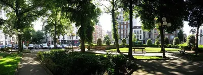 a park with benches and trees in a city at Flat Moliere in Brussels