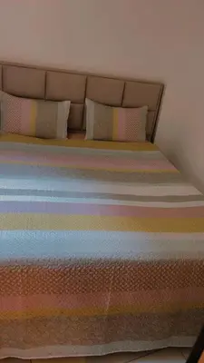 a bed with a rainbow striped comforter and pillows at Coumbis Faye in Brussels