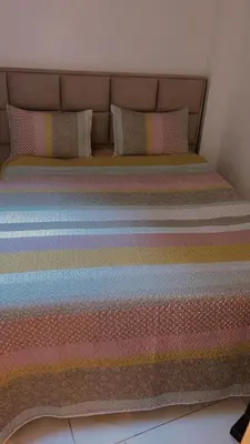 a bed with colorful striped sheets and pillows at Coumbis Faye in Brussels