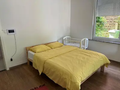 a bedroom with a bed with a yellow comforter and a window at Studio - simply living in Antwerp
