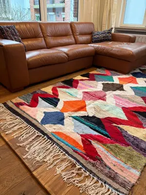 a brown leather couch in a living room with a colorful rug at Richard XIII in Antwerp