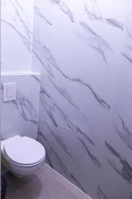 a bathroom with a toilet and a marble wall at Machelen in Machelen