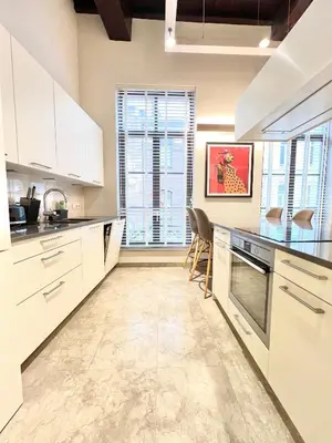 a kitchen with white cabinets and a large window at Luxury on Rue Haute in Brussels