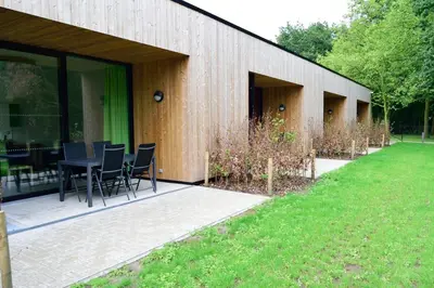 a building with a table and chairs in a yard at Bielebale Vakantiehuisjes in Brasschaat