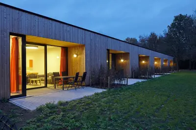 a building with glass doors and a table and chairs at Bielebale Vakantiehuisjes in Brasschaat