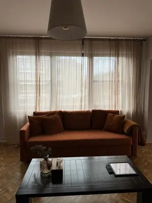 a living room with a brown couch in front of a window at Appartement Brussels Expo in Strombeek-Bever