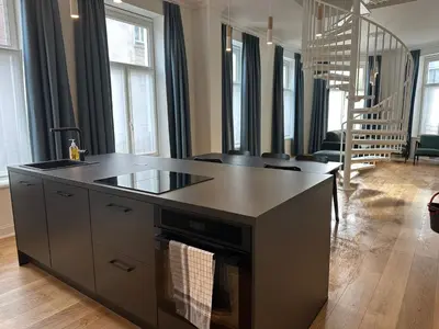 a kitchen with a black island in a living room at Charming Ixelles Apartment Retreat in the Heart of Brussels in Brussels