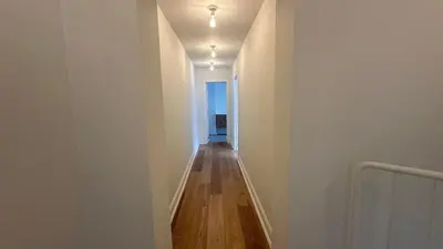 a hallway with white walls and a wooden floor at Charming Ixelles Apartment Retreat in the Heart of Brussels in Brussels