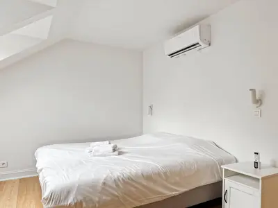a white room with a bed with a white sheets at Charming Ixelles Apartment Retreat in the Heart of Brussels in Brussels
