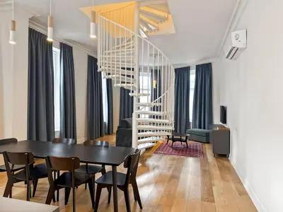 a dining room with a table and chairs and a staircase at Charming Ixelles Apartment Retreat in the Heart of Brussels in Brussels