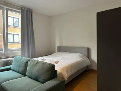 a bedroom with a bed and a couch and a window at Charming Uccle Apartment with City Views in Brussels