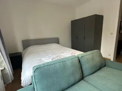 a bedroom with a bed and a couch and a cabinet at Charming Uccle Apartment with City Views in Brussels