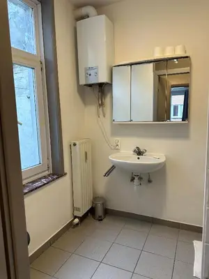 a bathroom with a sink and a mirror and a window at Charming Uccle Apartment with City Views in Brussels