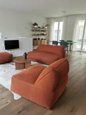 a living room with two orange couches and a tv at Living Gent in Ghent