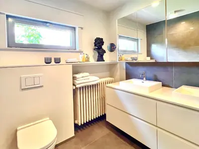 a bathroom with a sink and a toilet and a window at B&B near Ghent in Merelbeke