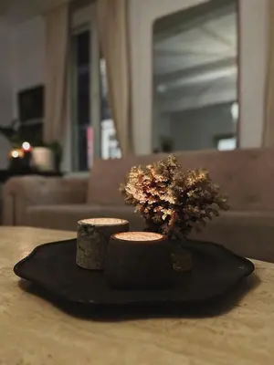 a black plate with two candles and flowers on a table at Gent Gently apartment in center in Ghent
