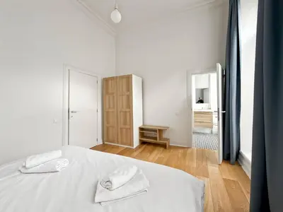 a white bedroom with a bed with two towels on it at self check in Ixelles Apartment Retreat in the Heart of Brussels in Brussels