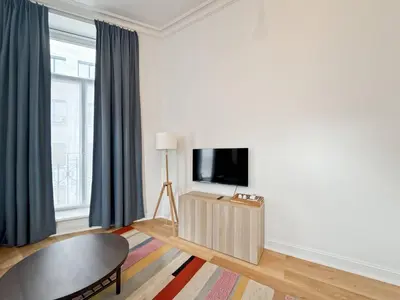 a living room with a tv and a table at self check in Ixelles Apartment Retreat in the Heart of Brussels in Brussels