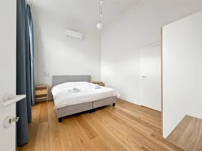 a white bedroom with a bed and a mirror at self check in Ixelles Apartment Retreat in the Heart of Brussels in Brussels