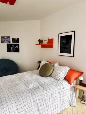 a bedroom with a bed with an orange pillow on it at Garden flat in central brussels in Brussels