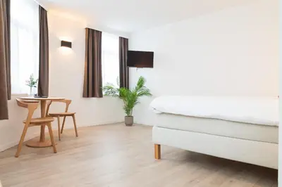 a bedroom with a bed and a table and windows at SAFIR by Domani Hotels in Aalst