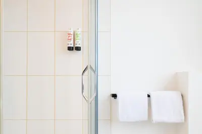 a bathroom with white towels on a glass shower door at SAFIR by Domani Hotels in Aalst