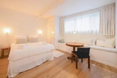 a bedroom with a bed and a table and a window at Studio Lido by Simone Antwerp in Antwerp