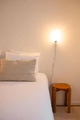 a bed with a light on the wall next to a table at Studio Lido by Simone Antwerp in Antwerp