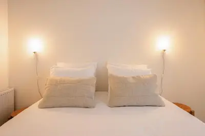 a bed with two pillows and two lights on top at Studio Lido by Simone Antwerp in Antwerp
