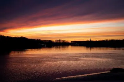 a sunset over a large body of water at Waterfront vacation home in Sint-Amands