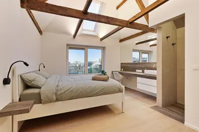 a bedroom with a bed and a bathroom with a sink at Luxury escape in the heart of historic Mechelen in Mechelen