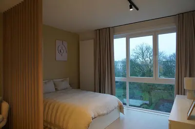 a bedroom with a bed and a large window at Cosy and Fully Equipped Studio in Antwerp