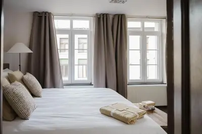 a bedroom with a large white bed with two windows at Apartment in the House of the Harbor Captain in Antwerp