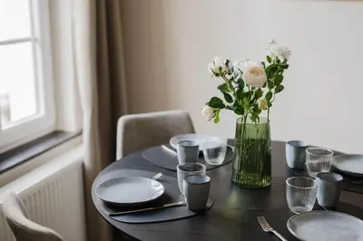 a table with plates and a vase of flowers on it at Apartment in the House of the Harbor Captain in Antwerp