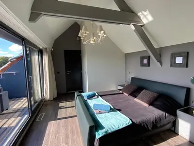 a bedroom with a bed and a balcony at Escape to Unwind in Putte