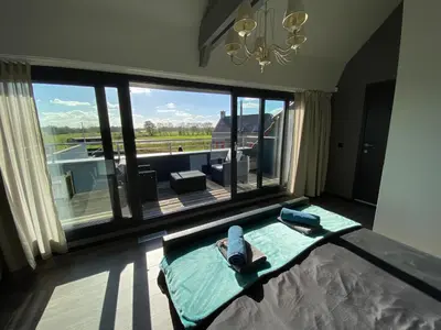 a woman laying on a bed in a room with a large window at Escape to Unwind in Putte